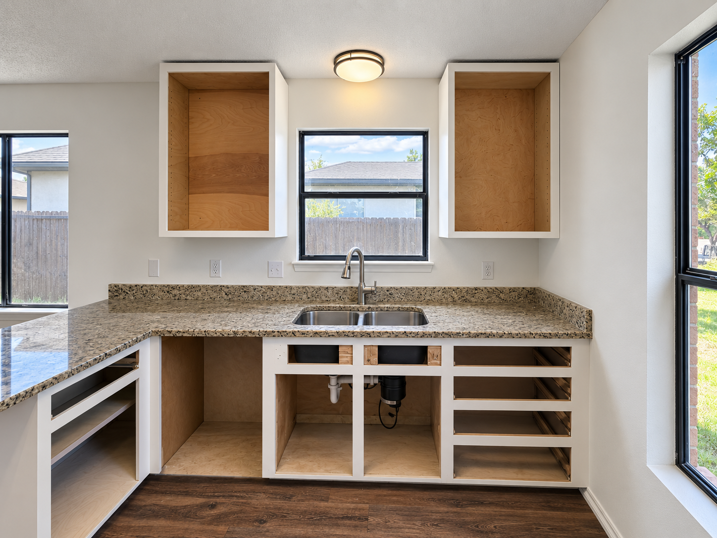 Kitchen during renovation with new upper cabinet boxes installed and existing lower cabinets prepared for refacing